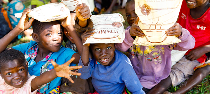 670x300_Day1_03_NuSkin Children from the Mtendere Orphanage pose for a picture with their bags of Vitameal given to them from the Nourish The Children Initiative.